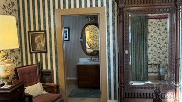 Une chambre à coucher avec un lit, une chaise, un bureau et un miroir.
