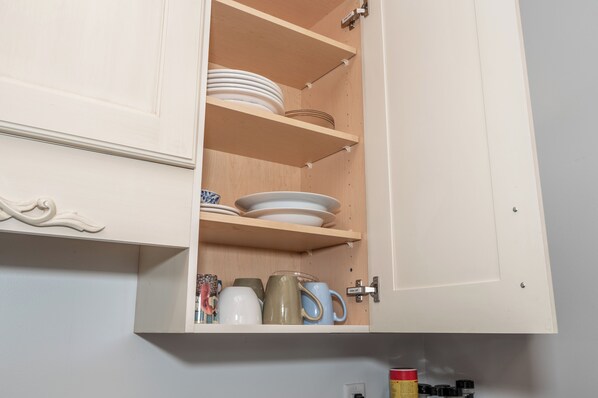 A kitchen cabinet with shelves holding plates, bowls, and mugs. - Spacious 5-bedroom house in Covington- minutes from Downtown Cincy (Covington)