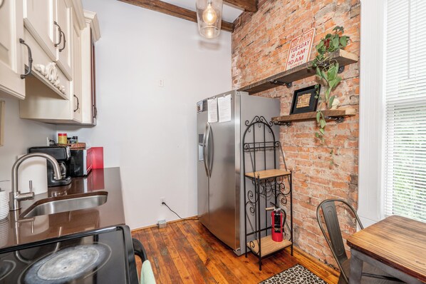A compact kitchen with a stainless steel refrigerator, a sink, and a wooden dining table. - Spacious 5-bedroom house in Covington- minutes from Downtown Cincy (Covington)