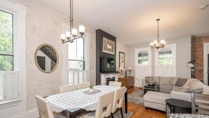 A dining area with a round table and chairs, a fireplace, and a television.