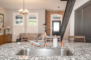 A kitchen with a granite countertop, stainless steel sink, and a wooden chair. - Spacious 5-bedroom house in Covington- minutes from Downtown Cincy (Covington)