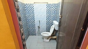 Uma casa de banho pequena com sanita, chuveiro e chão em mosaico.