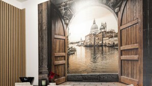 Un comedor con mesa y sillas de madera, vista a un canal con edificios, y un panel de pared de madera.