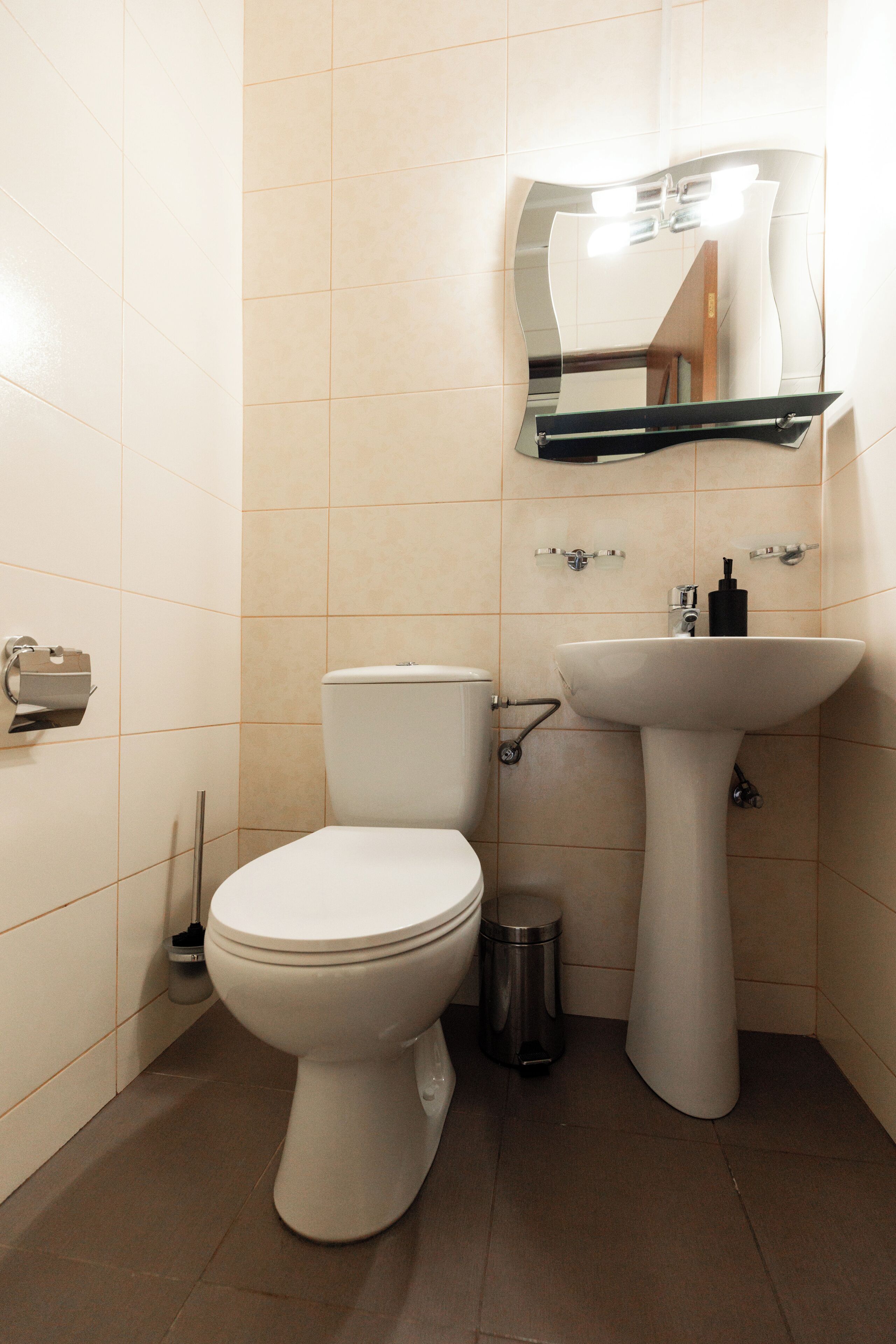Une petite salle de bain avec des toilettes, un lavabo et un miroir.