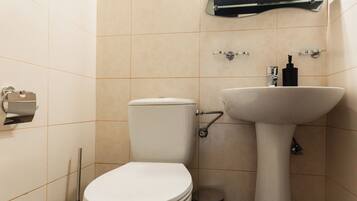 Une petite salle de bain avec des toilettes, un lavabo et un miroir.