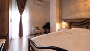 Una habitación de hotel con cama, escritorio, silla y ventana con cortinas.
