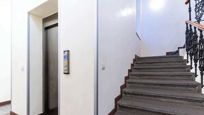Un escalier avec une rampe métallique et une porte donnant accès à un ascenseur.