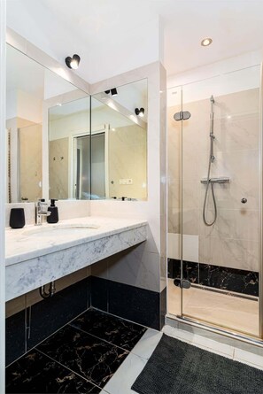 A modern bathroom with a marble vanity, a glass shower enclosure, and a large mirror. - Golden Dog Kingdom (Hlavní mesto Praha)