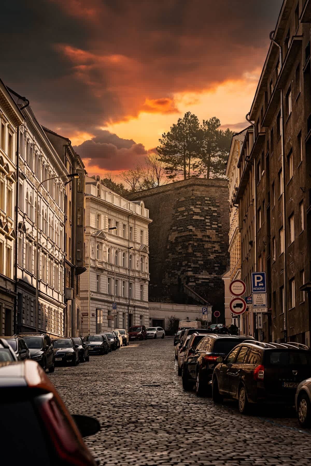 Eine Kopfsteinpflasterstraße gesäumt von parkenden Autos und historischen Gebäuden.