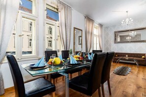 A dining area with a glass table, black chairs, and a fruit bowl. - Golden Dog Kingdom (Hlavní mesto Praha)