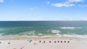 A beach with clear skies, calm sea, and several umbrellas and beach chairs. - Windemere 1206 (Pensacola)