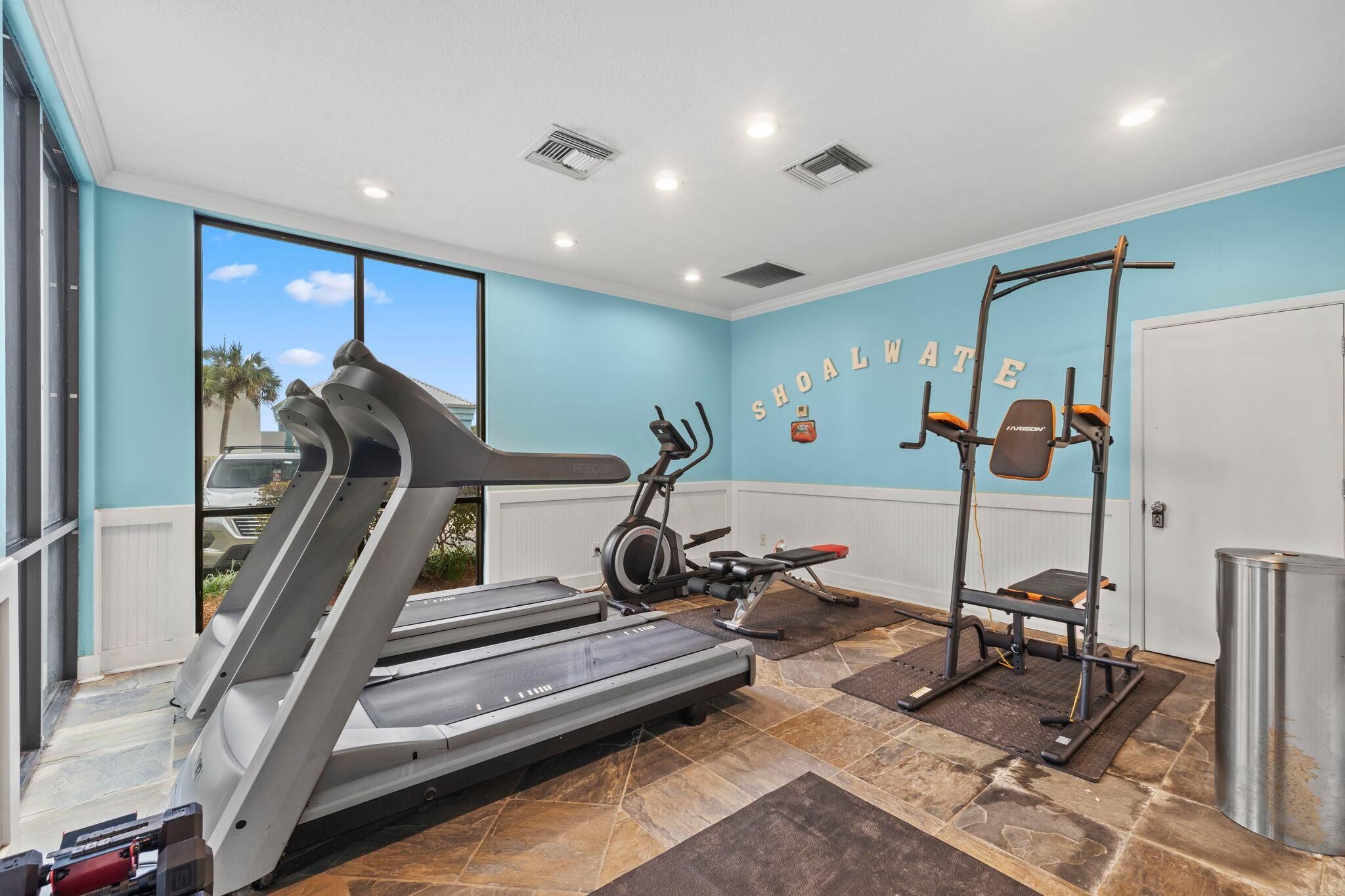 A home gym with a treadmill, elliptical, and weight bench.