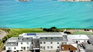 Ein Gebäude an der Küste mit mehreren Etagen, einem Parkplatz und Blick aufs Meer.