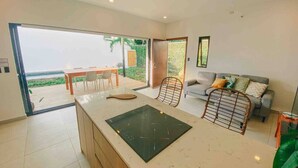 A modern kitchen with a large island, a dining area with a table and chairs, and a living area with a sofa and a TV. - Villa Uma • 50m to Zonte wave • 2Bdr (El Zonte)