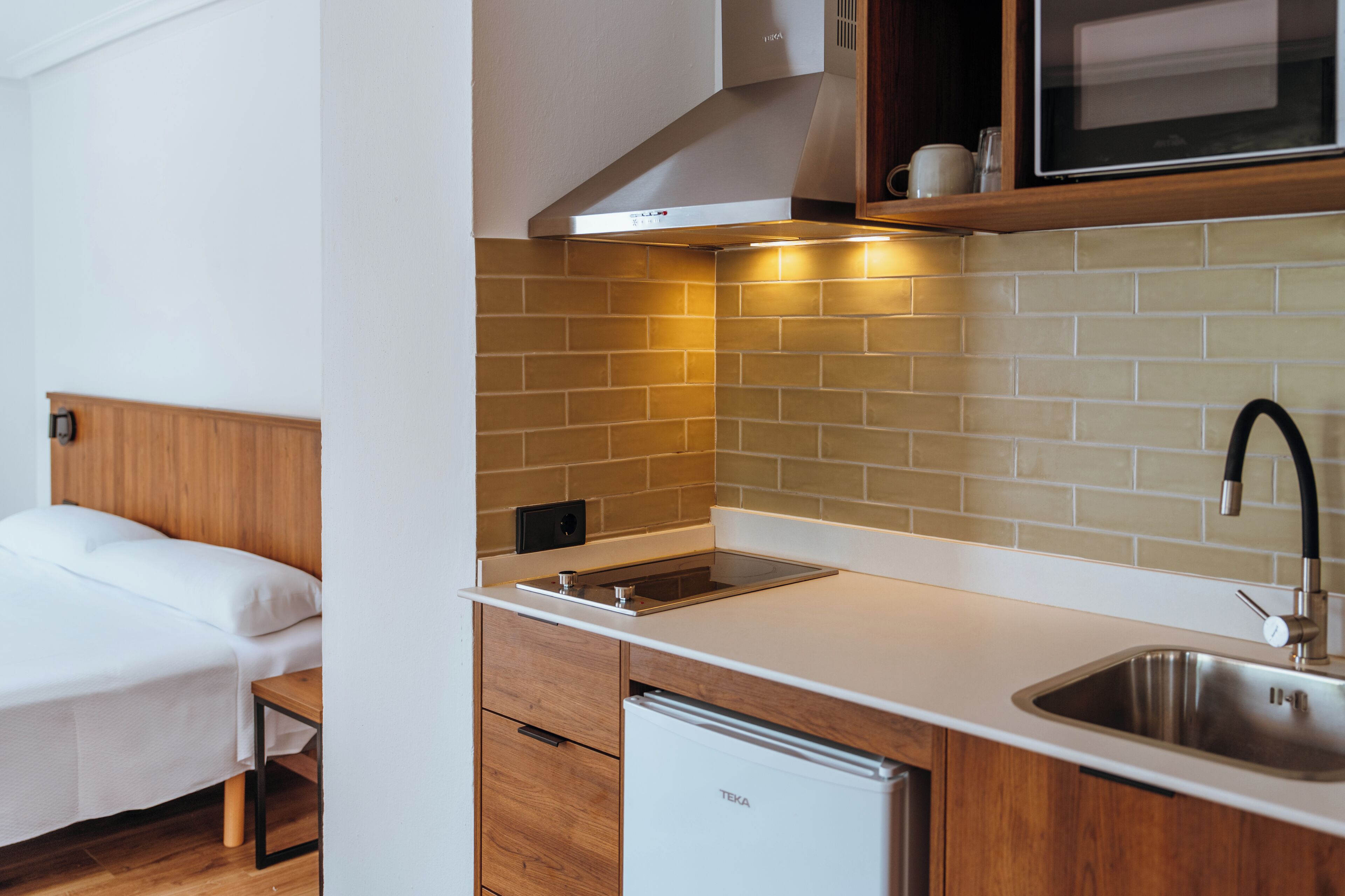 Una kitchenette compacta con estufa integrada, un lavamanos y un microondas.
