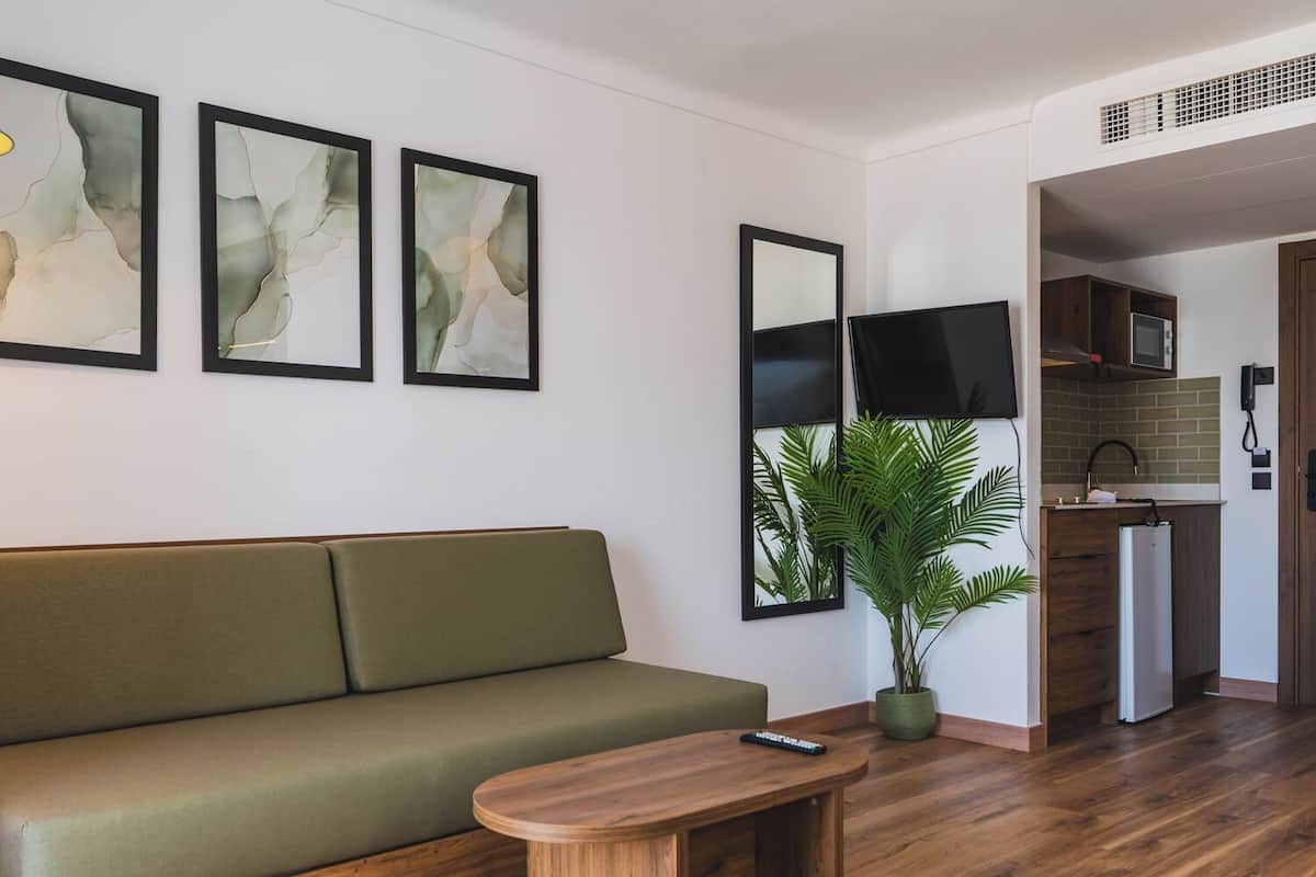 A modern living room with a green sofa, a wooden coffee table, and abstract artwork on the wall.