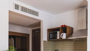 Una cocina compacta con armarios de madera, un refrigerador blanco, un microondas y un lavamanos.
