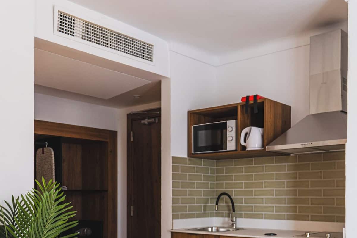 A compact kitchen with wooden cabinets, a white refrigerator, a microwave, and a sink.