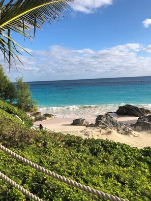 A beach with clear turquoise water, rocky outcrops, and lush greenery.