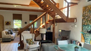 Ein großzügiges Wohnzimmer mit einer hohen Holztreppe, einem Glastisch und einer gemütlichen Sitzecke.