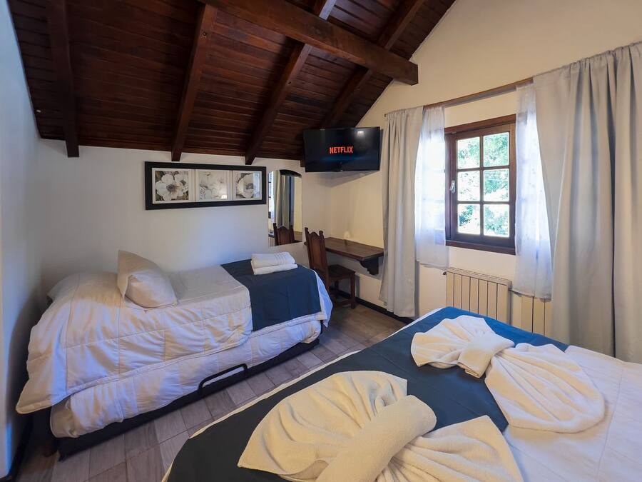 Una habitación acogedora con dos camas, televisión y ventana con cortinas.
