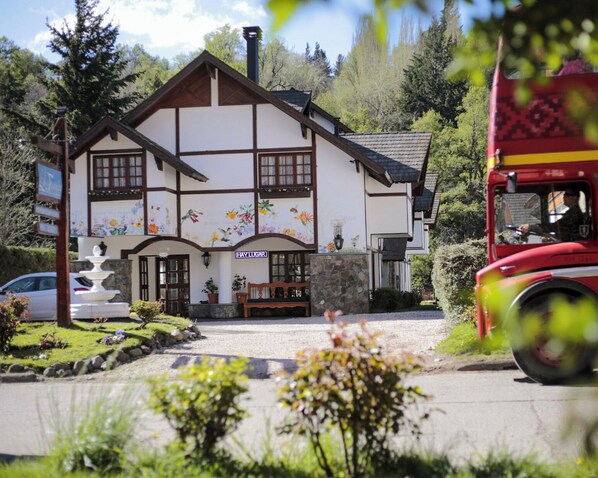 Un bâtiment traditionnel avec une façade en pierre, un banc en bois et une fontaine à l’avant.