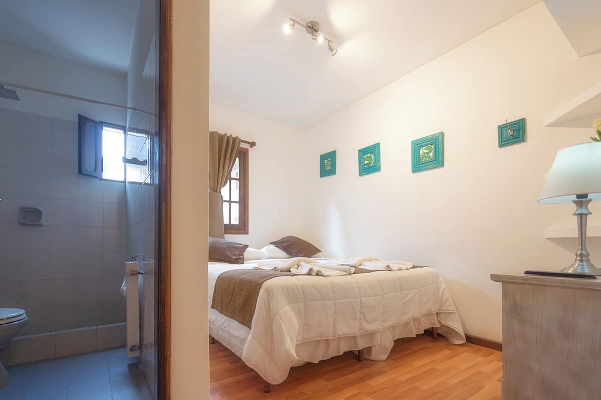 A bedroom with a bed, a bedside table, a lamp, and a window with curtains.
