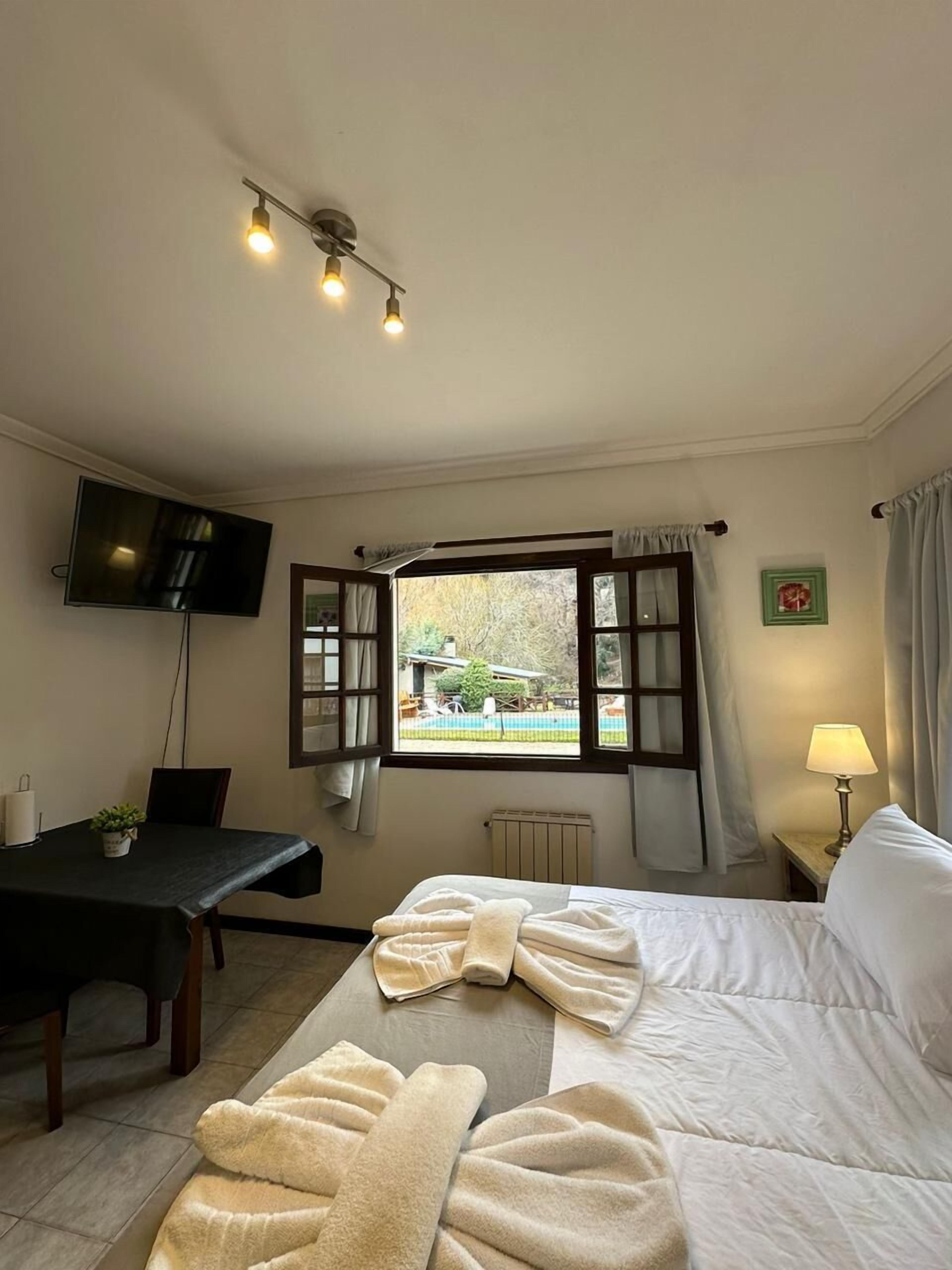 Une chambre d’hôtel avec un lit, un bureau, une télévision, une fenêtre avec des rideaux et une vue sur l’extérieur.