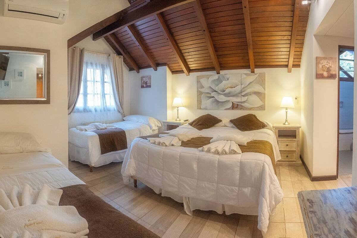 A hotel room with two beds, a large floral artwork on the wall, and a wooden ceiling.