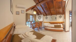 Habitación de hotel con dos camas, techo de madera, comedor con mesa y sillas, y un reloj en la pared.