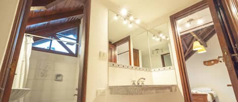 Un baño con ducha, inodoro, lavabo y un espejo grande.