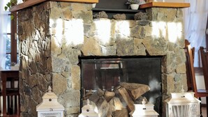 Una chimenea de piedra con un conducto negro, rodeada de faroles blancos y adornos decorativos.