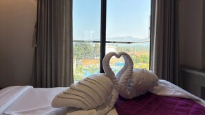 Ein Hotelzimmer mit Bett, einer violetten Steude und einem Fenster mit Vorhängen.