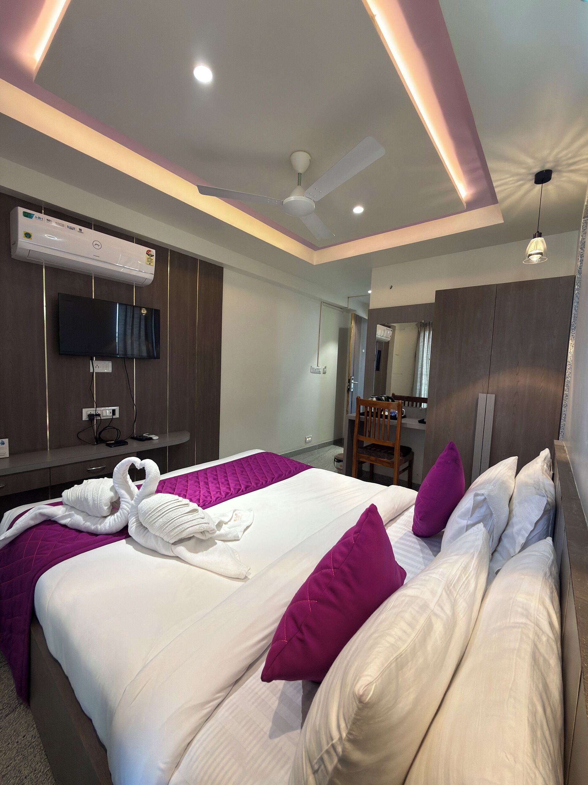 Une chambre d’hôtel moderne dotée d’un grand lit, d’une télévision à écran plat, d’un système de climatisation et d’un ventilateur de plafond.