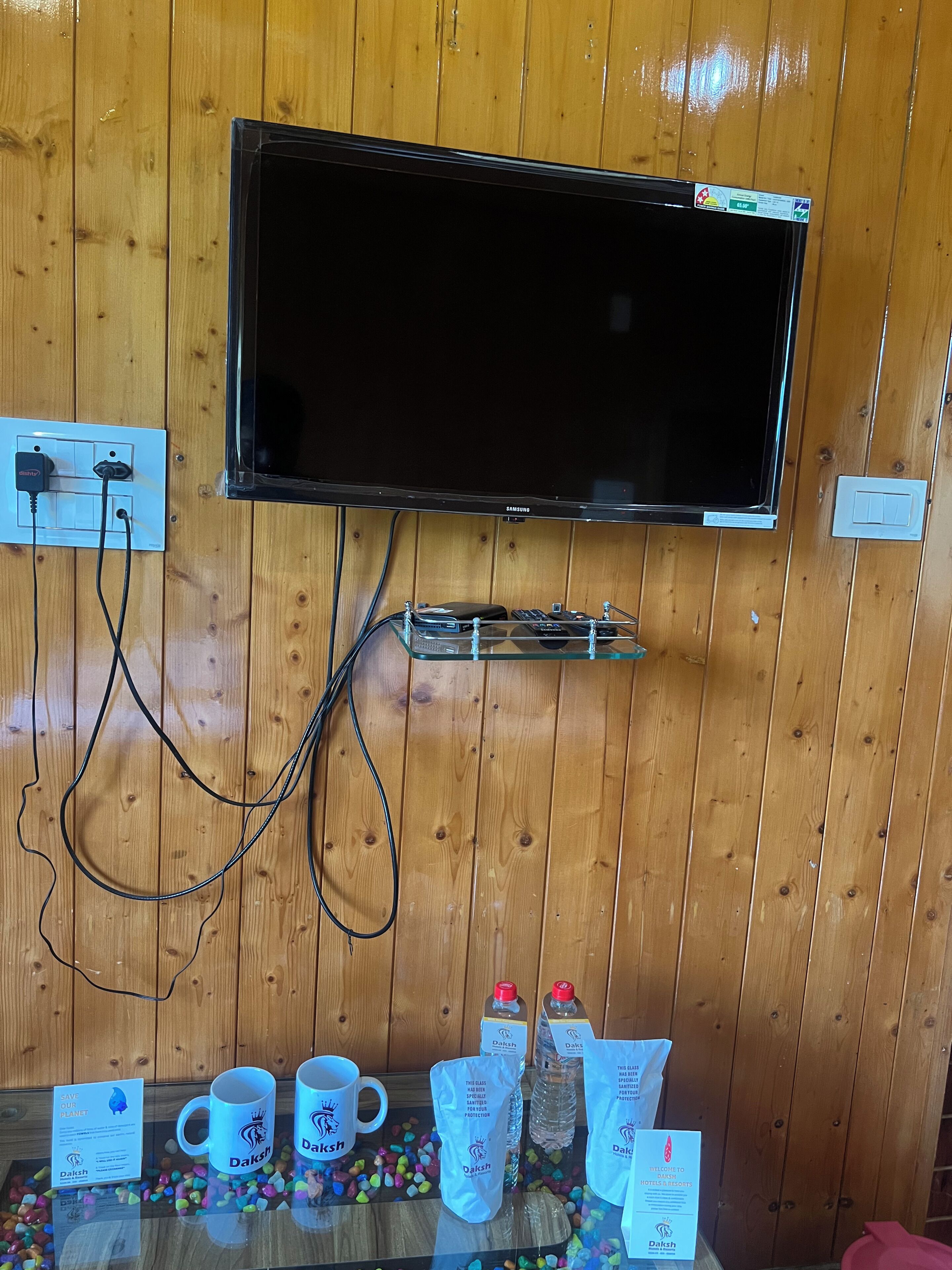 A television mounted on a wooden wall with a power outlet and cable management.