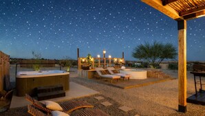 Un bain à remous, des chaises longues et une pergola sous un ciel étoilé.