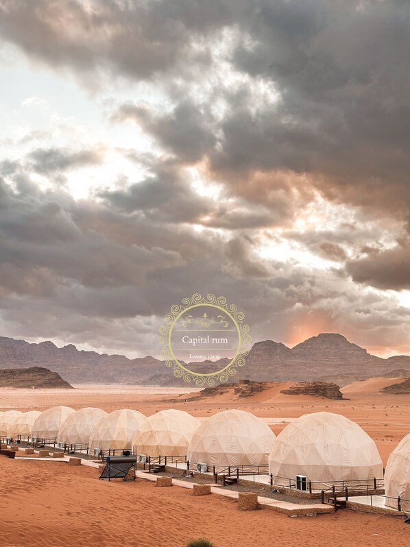 A desert landscape with multiple dome-shaped tents arranged in rows, suggesting a camp or resort setting. - Capital Rum Luxury Camp (Wadi Rum)