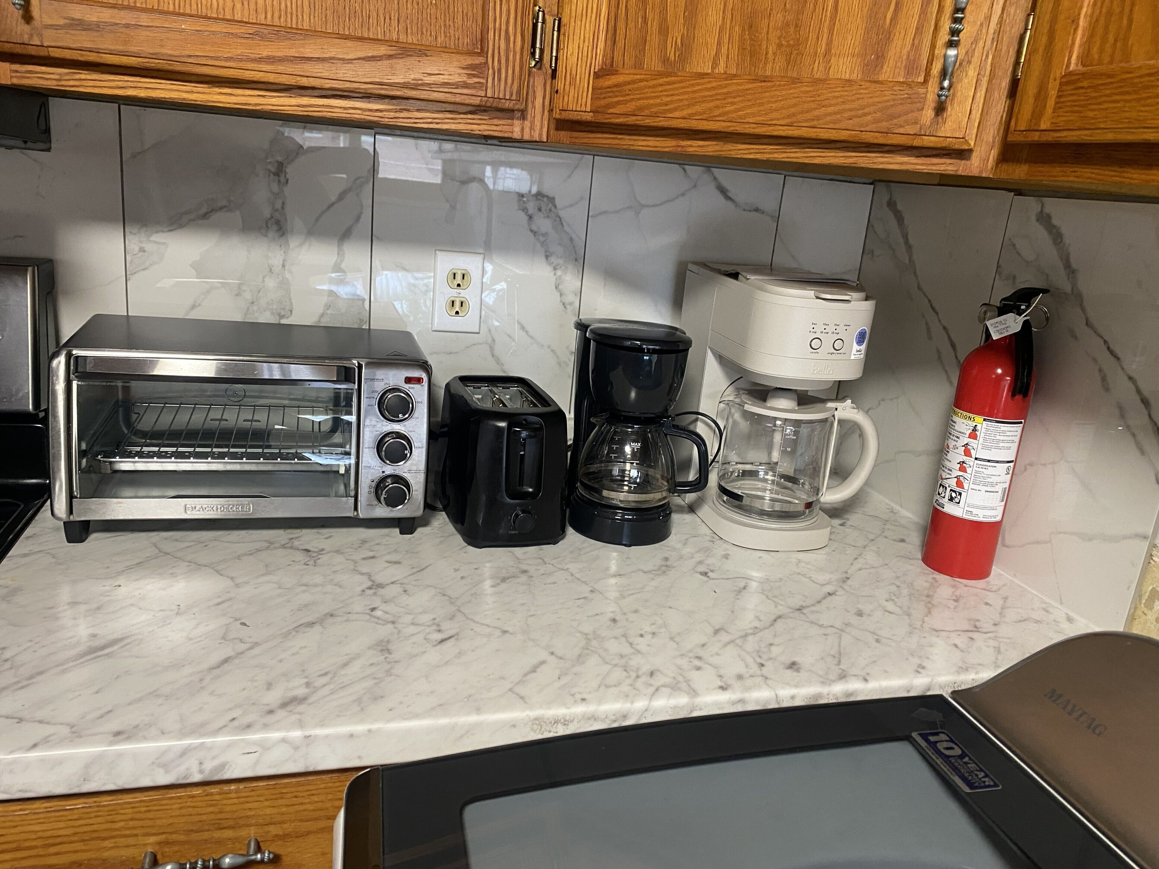 Una cocina con tostadora, cafetera y extintor.