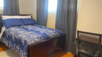 A bedroom with a bed, a chair, and a window with curtains.