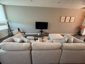 A modern living room with a sectional sofa, a flat-screen TV, and a coffee table. - The Imagination House! (Seattle)