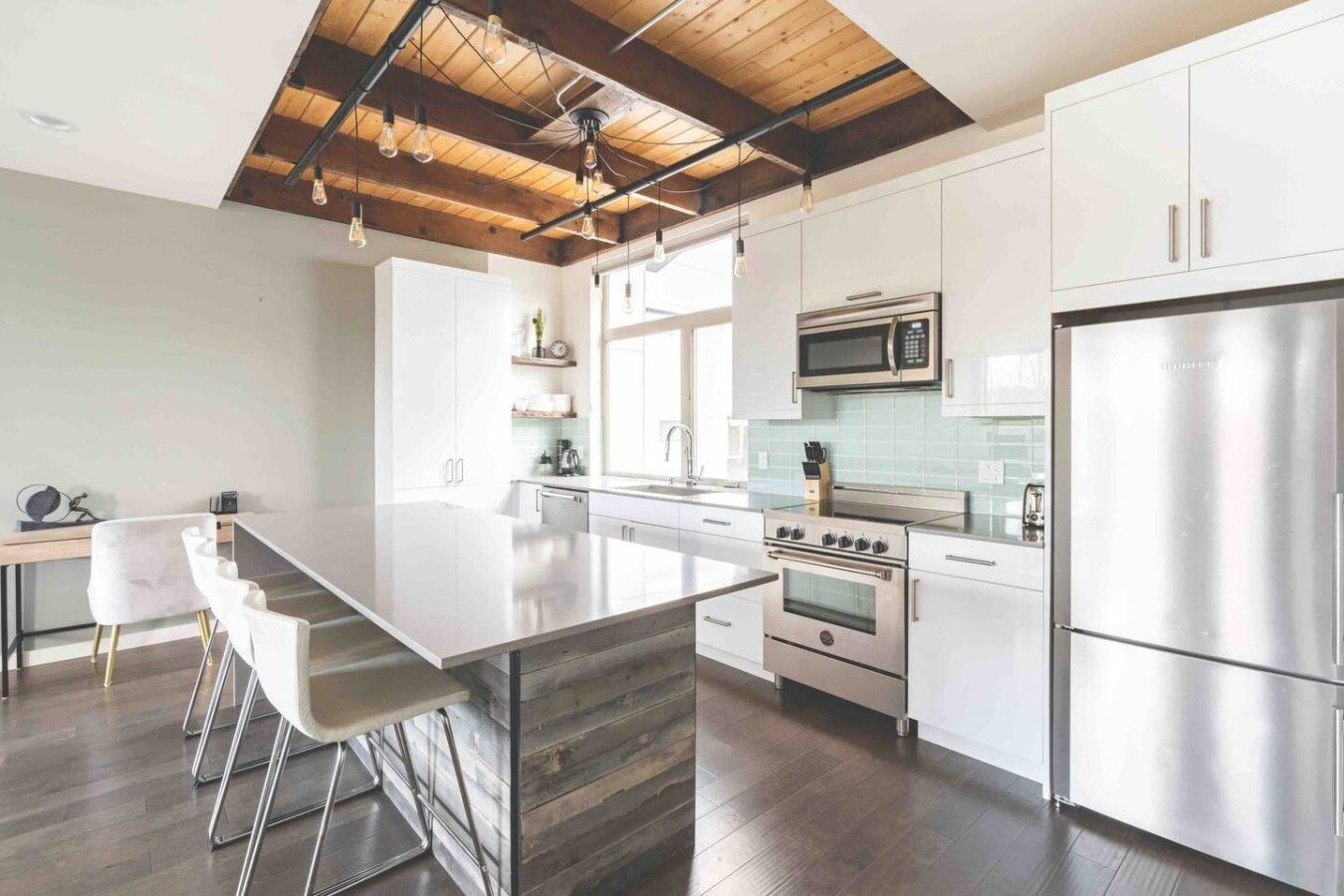 A modern kitchen with a central island, stainless steel appliances, and a wooden ceiling.