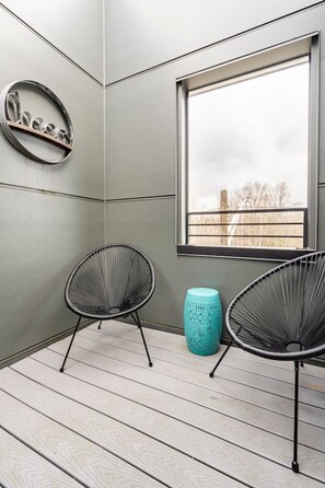 A room with two black wireframe chairs, a teal stool, and a window with a view of trees. - The Imagination House! (Seattle)