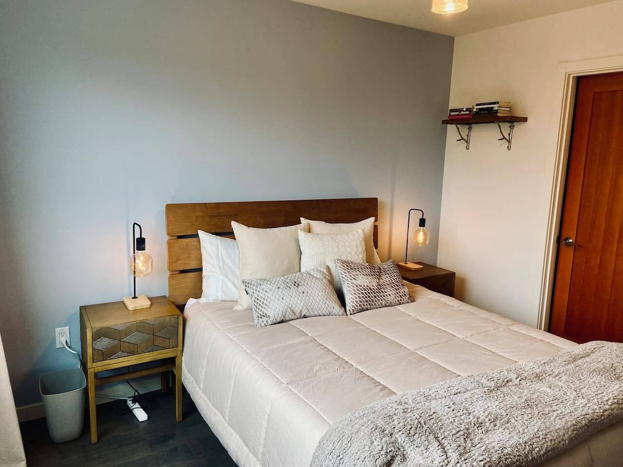 Een slaapkamer met een bed, nachtkastjes, een wandplank en een deur.