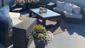 An outdoor patio with wicker furniture, a table with flowers, and a large umbrella.