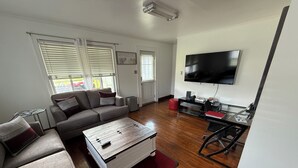 A modern living room with a sofa, coffee table, and a flat-screen TV mounted on the wall.