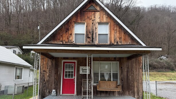 A wooden house with a red door, a porch, and a sign that reads "Summers House."