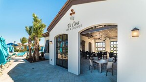 Zona de bar y salón con asientos exteriores y vista a la piscina.