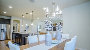 Un comedor moderno con una mesa de madera, sillas blancas y una araña.