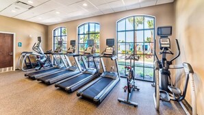 Un gimnasio con cintas de correr, elípticas y bicicletas estáticas.