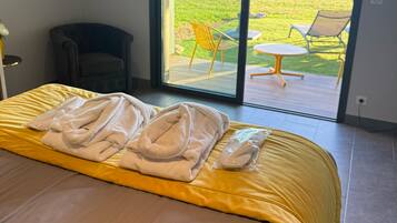 A bedroom with a bed, a chair, and a view of a garden through a sliding door.